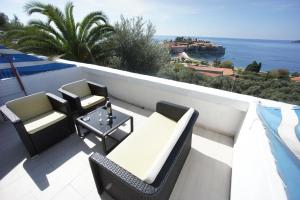 a balcony with a table and chairs and the ocean at Vila Mitrovich in Sveti Stefan