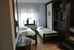Habitación pequeña con 2 camas y mesa. en Zajazd pod Zamkiem en Kętrzyn