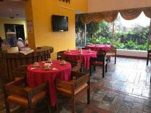 una sala da pranzo con tavoli e sedie rossi e una TV di Hotel Savoy Inn a Quito
