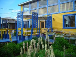 un edificio amarillo con mesas y sombrillas azules y amarillas en Gîte des Hauteurs et Café de la place en Saint Zenon