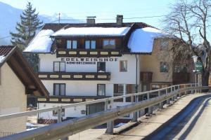 a building with snow on top of it next to a road at Edelweisshof in Birnbaum