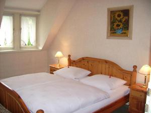 a bedroom with a bed with white sheets and two lamps at Pension Haus Weller in Boppard