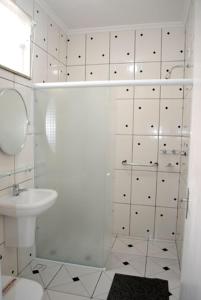 a white bathroom with a shower and a sink at Hotel Aliança in São Lourenço