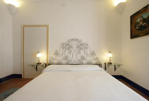 un letto bianco in una stanza con due lampade sui tavoli di Novecento a Trapani