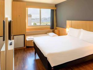 um quarto de hotel com uma cama grande e uma janela em ibis Rio de Janeiro Santos Dumont no Rio de Janeiro