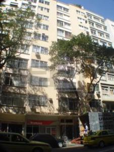 un edificio blanco alto con coches estacionados frente a él en Apartamento Copacabana Mar, en Río de Janeiro