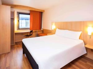 Un dormitorio con una gran cama blanca y una ventana en Ibis Madrid Alcobendas, en Alcobendas