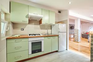 eine Küche mit grünen Schränken und einem weißen Kühlschrank in der Unterkunft Alto Apartments in Umag