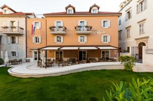 un gran edificio con un patio con mesas y sillas en Hotel Marul, en Split