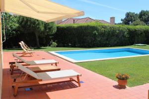 a patio with two chairs and an umbrella and a pool at Dunas Golf House in Cascais
