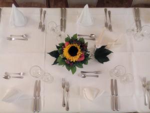 ein weißer Tisch mit Besteck und Sonnenblume darauf in der Unterkunft Hotel Restaurant Lütkebohmert in Reken