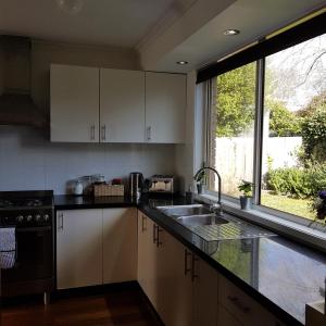 a kitchen with white cabinets and a sink and a window at Belle in Bowral in Bowral