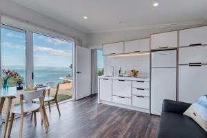 a kitchen with white cabinets and a table and a dining room at Woodside Bay Chalets in Ostend