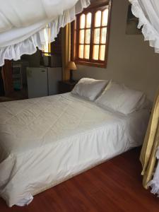 a large bed with white sheets and pillows at La Maison des Fous in Papudo