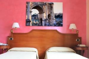 two beds in a room with a pink wall at Hotel Kent in Rome