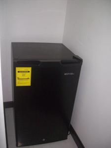 a black refrigerator with a yellow sign on it at Alojamientos Turisticos Titanic in San Andrés