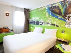 1 dormitorio con cama blanca y pared verde en Ibis Styles Lyon Villeurbanne Parc de la Tête d'Or, en Villeurbanne