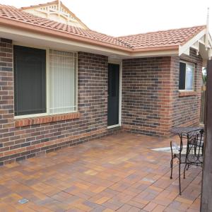 a patio with chairs and a table on a brick house at Oasis on Marsh in Armidale