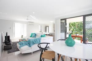 a white living room with a table and a couch at Beach Breeze Holiday House in Mackay