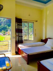 a bedroom with two beds and a large window at Huyen Tram Guesthouse in Dồng Văn