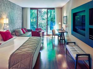 a bedroom with a bed and a living room at Mercure Iguazu Hotel Iru in Puerto Iguazú