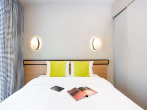 a bedroom with a white bed with yellow pillows at Aparthotel Adagio access München City Olympiapark in Munich