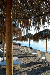 a row of chairs and straw umbrellas on a beach at Xanthippi Hotel in Souvala