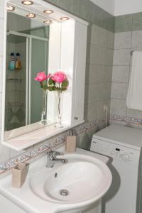 a bathroom with a sink and a vase with pink flowers at Barbati Pietre Di Mare in Barbati +36 photos