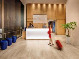 a woman with a suitcase walking through a lobby at Travelodge Dongdaemun Seoul in Seoul