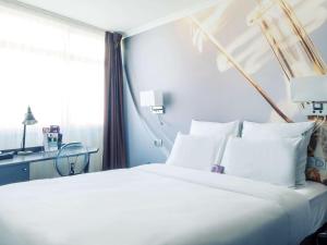 ein Schlafzimmer mit einem großen weißen Bett und einem Fenster in der Unterkunft Mercure Paris Malakoff Parc des Expositions in Malakoff