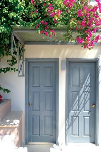 two blue doors on a white building with pink flowers at Xanthippi Hotel in Souvala