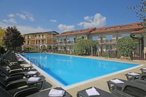 a large swimming pool with chairs and buildings at Hotel Splendid Sole in Manerba del Garda