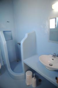 La salle de bains blanche est pourvue d'un lavabo et d'une douche. dans l'établissement Apollon Koufonisia Studios, à Koufonisia
