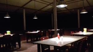 una sala da pranzo con tavoli, sedie e luci di River Near Coorg a Jambur