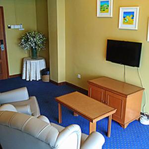 a living room with a couch and a flat screen tv at Hotel UiTM Shah Alam in Shah Alam