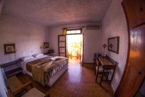 a bedroom with a bed and a table and a window at Vagia Traditional, Aegina Island in Vaia