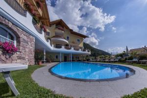 eine Villa mit Swimmingpool vor einem Gebäude in der Unterkunft Hotel Am Sonneck in Algund
