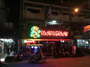 a man riding a motorcycle in front of a restaurant at night at Shanghai Guesthouse in Pattaya Central