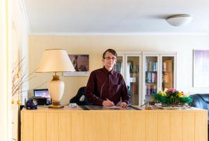 un hombre sentado en un escritorio en una oficina en Hotel Adler, en Wismar