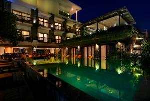 a building with a swimming pool at night at The Kirana Canggu Hotel in Canggu