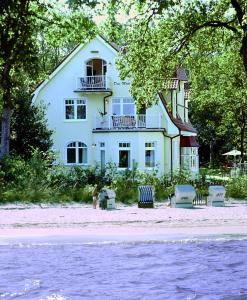 une grande maison blanche sur la plage au bord de l'eau dans l'établissement Strandvilla Drei Mäderl Haus, à Boltenhagen