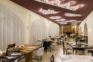 una sala da pranzo con tavoli, sedie e soffitti di Vinilia Wine Resort a Manduria