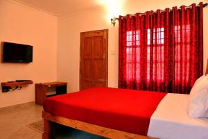 una camera con letto rosso e finestra di River Near Coorg a Jambur