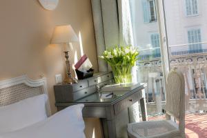 a bedroom with a desk with a lamp and a window at Le Cavendish in Cannes