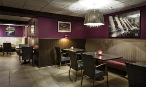a restaurant with purple walls and tables and chairs at Hotel Thermen Dilbeek in Dilbeek