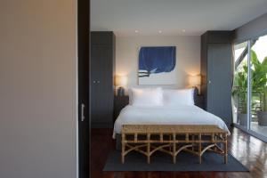 a bedroom with a bed with a blue painting on the wall at Mantra Samui Resort - Adults Only in Mae Nam