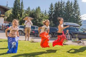 drie jonge meisjes rennen in het gras bij Appartements AUSZEIT with private SPA in Embach