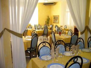 une salle remplie de tables et de chaises avec des murs jaunes dans l'établissement Hotel Massimino, à Anguillara Sabazia