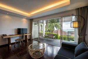 a living room with a couch and a desk and a television at Mantra Samui Resort - Adults Only in Mae Nam