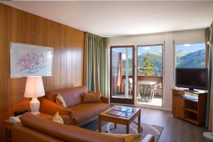 a living room with a couch and a television at Aparthotel Helvetia in Crans-Montana
